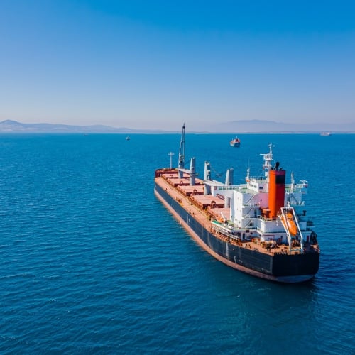 An aerial view of a bulk vessel for dry cargo in anchorage in sea waiting loading in industrial port